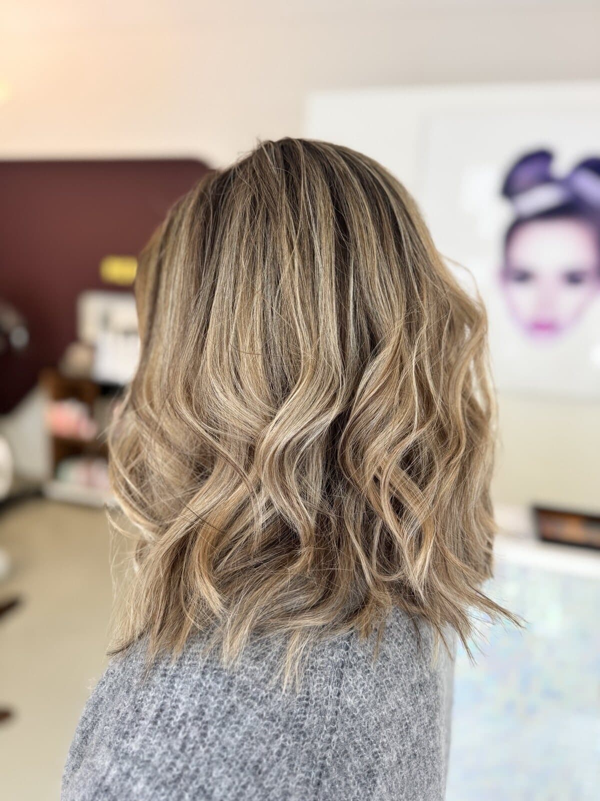 Blonde Strähnen in einem welligen Long Bob, vor der Weinwand